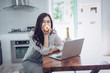 © Suntipong - Portrait of beautiful young latin woman talking over the phone while cooking in kitchen