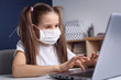 © Roman Pyshchyk - Distance learning online education. schoolgirl in medical mask studying at home, working at laptop notebook and doing school homework. covid quarantine concepte.