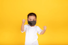 Little Asian Children Boy Wearing Medical Mask Protection Coronavirus COVID-19 Or Dust Pm2.5 Fighting Gesture Safety Healthy Self Air Pollution Concept On Yellow Background, Copy Space.