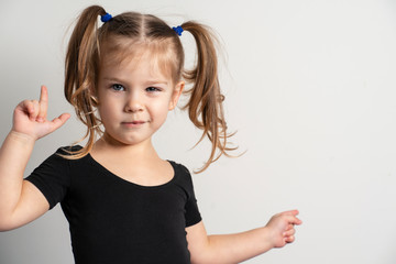 portret emotional 4 year old girl with two ponytails. one hand shows on copy space to the right of itself, the other is emotionally raised up