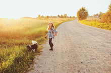 Happy Child Girl Walking Country Road With Her Dog. Enjoying Summer Vacations, Rural Living Concept
