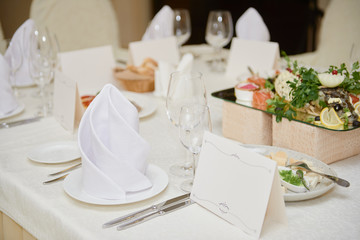 Table set with blank guest card, plate with serviette and cutlery on table, copy space. Place setting at wedding reception. Table served for wedding banquet in restaurant