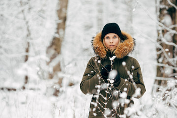 Girl on background of snowy trees on walk in winter forest in afternoon