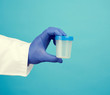 © nndanko - male doctor in a white coat holds a empty plastic container for urine specimen