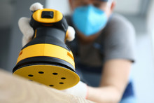 Male Handy Man Hold Yellow Grinder With Disc Sander In Hand Closeup Background. Professional Education Concept.