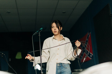 young woman with mic in music studio