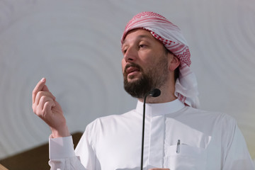 Poster - Muslims young arabic Imam has a speech on friday afternoon prayer in mosque. Muslims have gathered for the friday afternoon prayer in mosque and are listening to the speech of imam