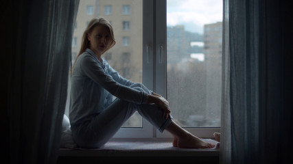 Young woman sitting on the window