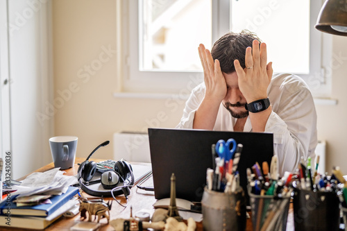 Fotomural Tired frustrated businessman working from home online sitting at home office with laptop during quarantine and self isolation period at pandemic