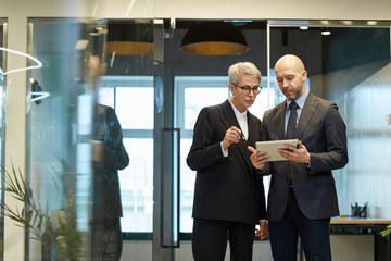 Portrait of successful mature woman talking to colleague in modern office interior, copy space