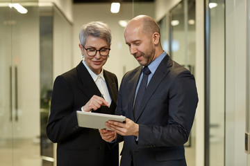 Wall Mural - Waist up portrait of successful mature woman talking to colleague in modern office interior, copy space