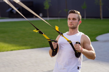 Sticker - Sportsman doing suspension straps exercises open air. Home workout routine. 