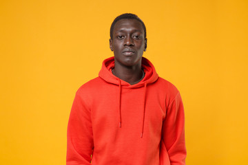 Handsome young african american man guy in red streetwear hoodie posing isolated on yellow background studio portrait. People sincere emotions, lifestyle concept. Mock up copy space. Looking camera.