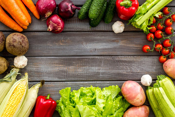 Set of autumn vegetables - potato, cucumber, carrot, greenery - on dark wooden background top-down copy space frame