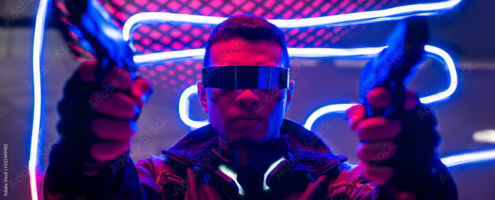 panoramic shot of mixed race cyberpunk player in futuristic glasses holding guns near neon lighting - obrazy, fototapety, plakaty 