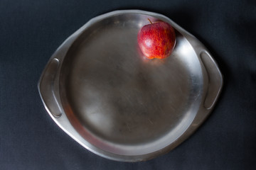 Wall Mural - Red apple on old steel plate and black background. Top view. Chiaroscuro. Snow white apple