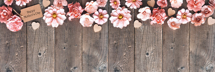 Wall Mural - Happy Mothers Day corner border with paper flowers and gift tag. Overhead view against a rustic wood banner background. Copy space.