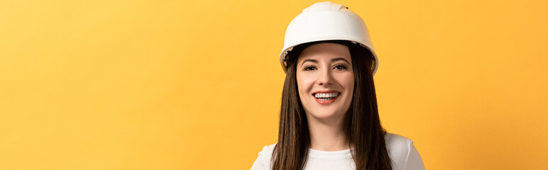 Wall Mural - panoramic shot of smiling handywoman looking at camera isolated on yellow