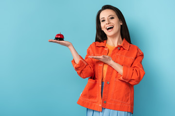 Wall Mural - smiling woman pointing with hand at service bell on blue background