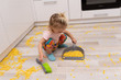 © Maria Mikhaylichenko - Cute little caucasian girl cleans the floor from cornflakes with scoop and brush at the kitchen.