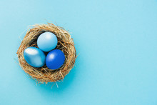Colored Easter Eggs In Nest Top Blue View Background, Selective Focus Image. Happy Easter Card