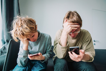 Wall Mural - father and son with mobile phones at home, family sad and stressed