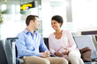© phocal Media - Businessman and businesswoman discussing at airport.
