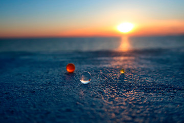 Wall Mural - three transparent glass balls lying on a concrete slab against the setting sun