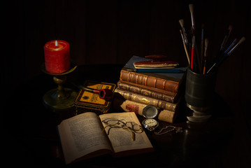 Wall Mural - An old desk with a pile of vintage brown leather books, an open book with eye glasses, a cup of coffee, a red candle with flame, a vintage pocket clock, earth globe.