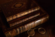 A vintage pile of three old brown leather books with eye glasses on a wood table.