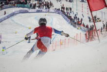 Telemark skier competing in downhill race, seen from the back while rushing towards the finish line