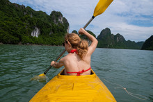 Back View Of Unrecognizable Woman In Swimsuit Paddling In Yellow Canoe During Vacation In Vietnam