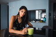© Kike Arnaiz/ADDICTIVE STOCK - Beautiful passionate brunette Hispanic woman in dress looking at camera and holding mug of hot drink at table with volume in room