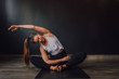 © JAKE JAKAB/ADDICTIVE STOCK - Young relaxed female with eyes closed and arm raised sitting in baddha konasana position on sports mat and practicing yoga in dark hall