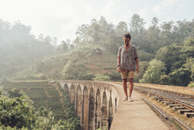 Full Length Of Male Traveler Walking On Edge Of Old Bridge With Railways And Tropical Plants On Background In Sri Lanka Asia 