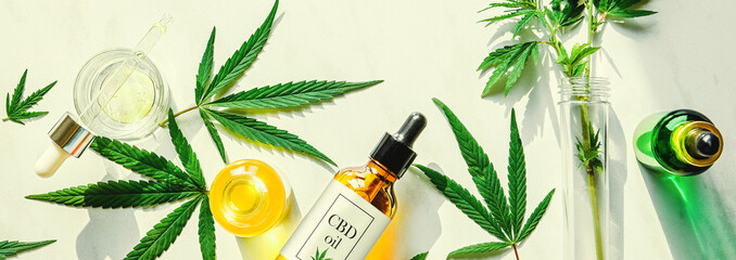 Various glass bottles with CBD oil, THC tincture and hemp leaves on a marble background. Flat lay, minimalism. Cosmetics CBD oil