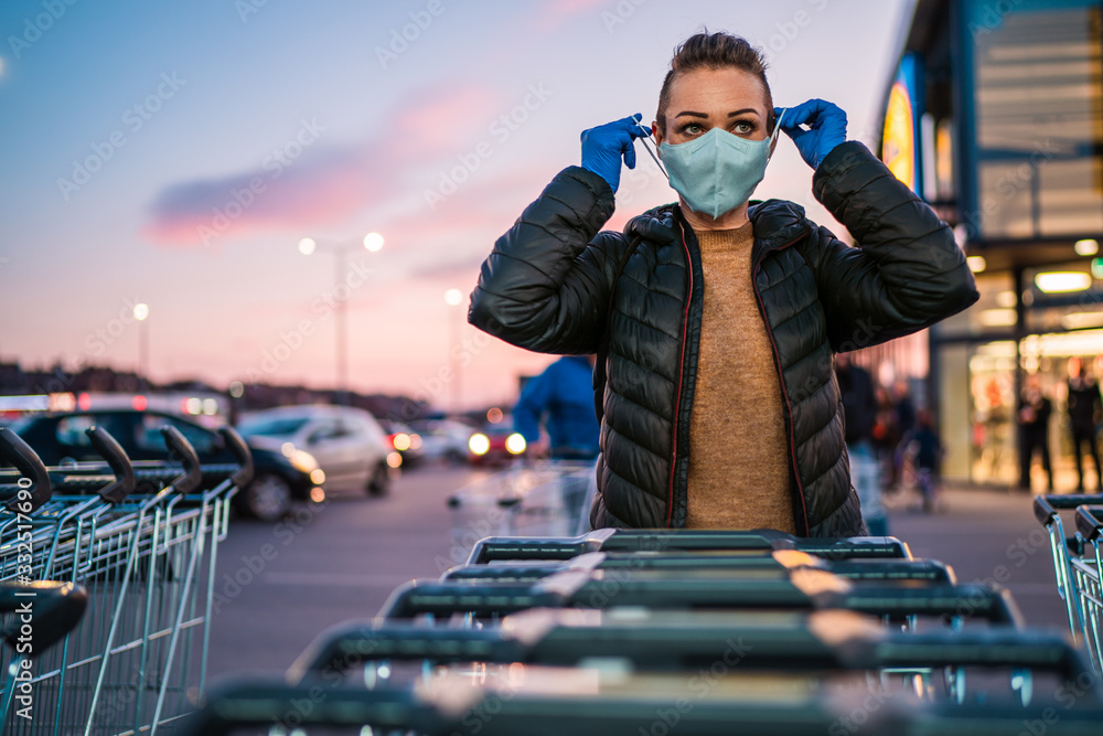 A woman wears medical protective gloves and a mask while shopping groceries. - obrazy, fototapety, plakaty 