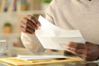 © PheelingsMedia - Black man hands putting a letter inside an envelope