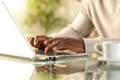 © PheelingsMedia - Black man hands typing on a laptop at home