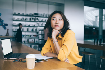 Asian smiling woman holding hands on chin at desk