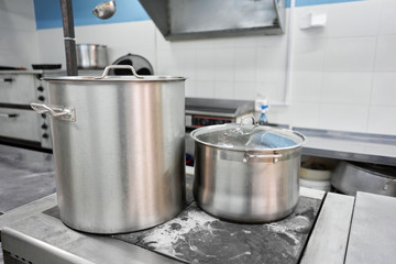 Wall Mural - Closeup of large pots on the stove. Chef cooking at commercial kitchen - hot job. real dirty restaurant kitchen.