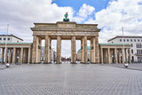 Fototapeta Paryż - berlin, germany, view on the famous Brandenburg gate on the 10. May square in Berlin city, parisian square without tourists and visitors - deserted, blue sky, small clouds