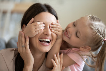 Canvas Print - Close up of cute little girl close smiling mother eyes have fun involved in funny activity at home, overjoyed small preschooler daughter play with happy young mom enjoy playful weekend time together