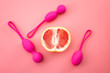 Metaphor for pelvic floor exercises, gynecology and treat urinary incontinence through strength exercise concept with kegel weights and half a grapefruit isolated on pink background