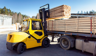 The machine loads the boards, lumber from the finished goods warehouse onto the truck