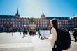 © eldarnurkovic - Visiting famous landmarks and places.Cheerful female traveler at famous Plaza Mayor square reading a map  admiring statue of Philip III. Marid,Spain travel experience.