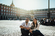 © eldarnurkovic - Visiting famous landmarks and places.Happy young couple tourists visiting famous Plaza Mayor square. Marid,Spain travel experience. Vacation in capital of Spain, blogger lifestyle.Europe honeymoon