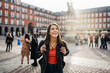 Leinwanddruck Bild - Young travel woman sightseeing urban outdoors.Traveling to Europe. Walking tour in Madrid.Backpack tourist experience.City girl.Cheerful tourist.Visiting Plaza Major square