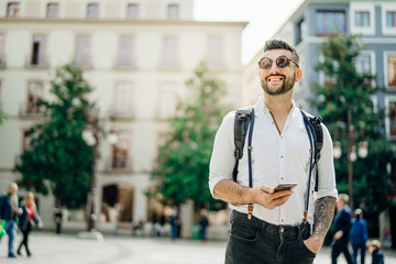 Young handsome man using smartphone in foreign country.Backpacker traveling the world.Staying connected.Tourist using local mobile network.Entrepreneur communicating.Using app for traveling.Mobile map