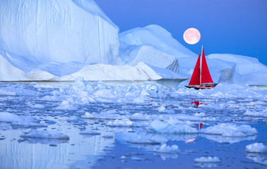 Wall Mural - sail boat with red sails cruising among ice bergs after sunset in front of a full moon. disko bay, g